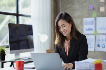 A beautiful Asian businesswoman sitting in her private office, she is checking company financial documents, she is a female executive of a startup company. Concept of financial management.