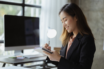 A beautiful Asian businesswoman sitting in her private office, she is checking company financial...
