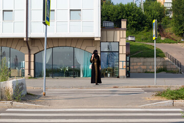 Muslim woman crossing the road during rush hour.