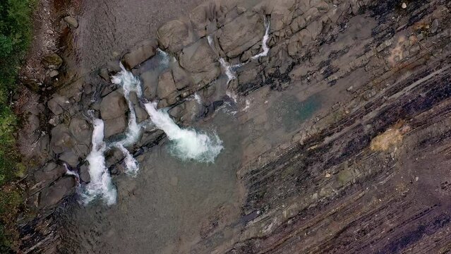 Aerial view of mountain river with cold clear water. The river flows over the stones with little waterfall.