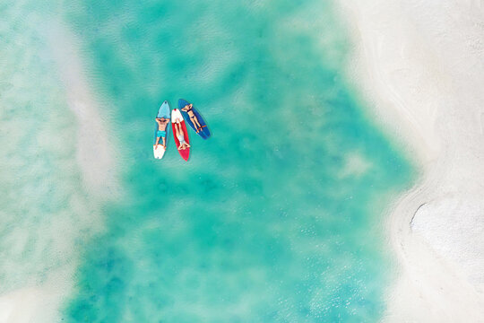 The family is resting lying on Sup boards in the turquoise sea. Three people ride sup boards in the ocean near the beach