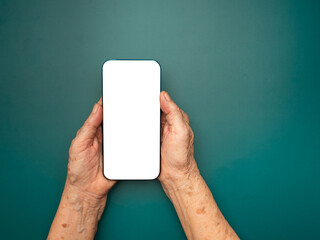 Top view of senior woman hand holding a mobile phone over a green background