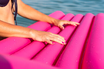 Sexy woman holding pink inflatable mattress in water