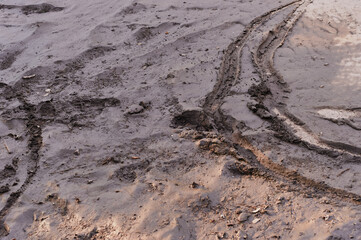 Footprints on drying road dirt after heavy rain. Bicycle and shoe prints. Summer evening