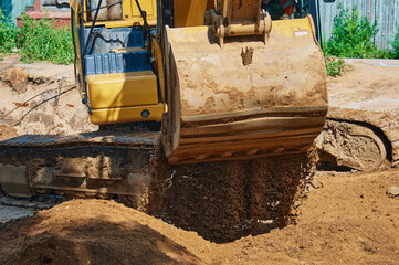 Close up view of an excavator bucket full of earth. The process of digging soil at a construction...