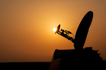 Live broadcast satellite antenna silhouette on an impressive summer sunset background. The dish...