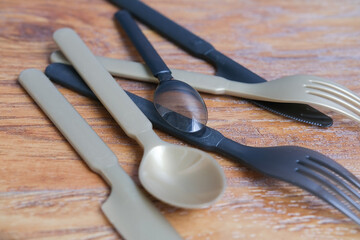 colored  plastic cutlery set on wooden table, gold and black knives, spoons, forks 