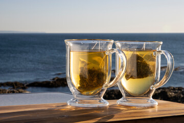 Pair of transparent tea cups with tea and lemon on wood in North Devon UK