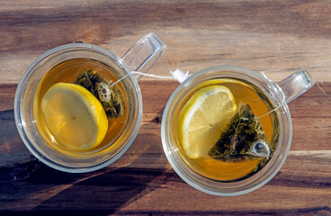 Pair of transparent tea cups from above with tea and lemon on wood in North Devon UK