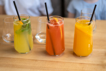 Colorful drinks or cocktails with straw on table in the cafe. Colorful fruit juices and lemonade. Soft drinks.