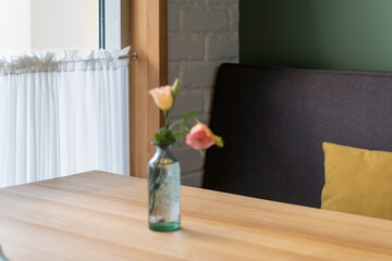 Interior of the cafe. Bottle with fresh flowers on table in cafe on sofa and window background. Cozy atmosphere in coffee shop.