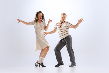 Excited young man and woman in retro style outfits dancing lindy hop isolated on white background....