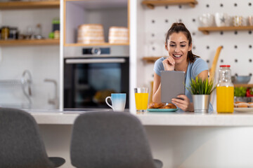 Obraz na płótnie Canvas Woman using digital tablet while having breakfast