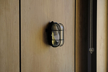 Turned off Industrial style metal black wall lamp. Wall hanging lamp on a brown wooden wall, night...