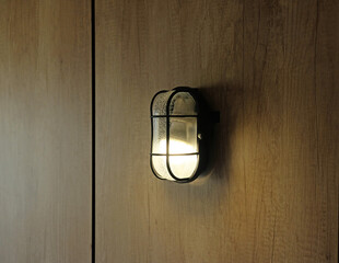 Turned off Industrial style metal black wall lamp. Wall hanging lamp on a brown wooden wall, night...