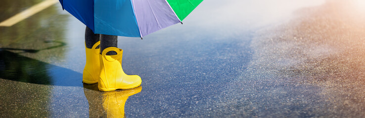 Child standing in the puddle in yellow rubber boots