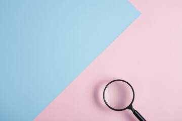 Magnifying glass on pastel pink and blue background
