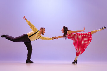 Active and emotional couple in colorful retro style costumes dancing incendiary dances isolated on...