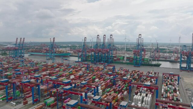 Fly above large logistic areal in harbour. Thousand of containers waiting for delivery to customer. Heavy cranes loading and unloading units from huge overseas cargo ships. Hamburg, Germany
