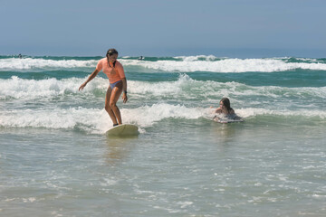 Two sisters surfing together in the waves in summer