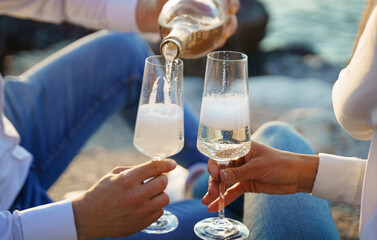 Hands holding champagne glasses over the sea