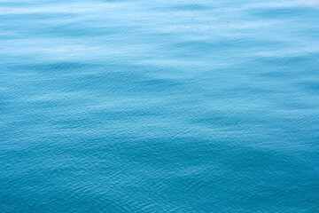 Turquoise blue colored calm sea surface texture.