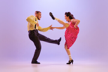 Beautiful girl and man in colorful retro style costumes dancing incendiary dances isolated on lilac...