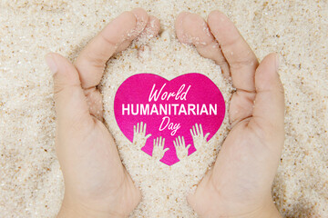 Hands hold sand with world humanitarian day text