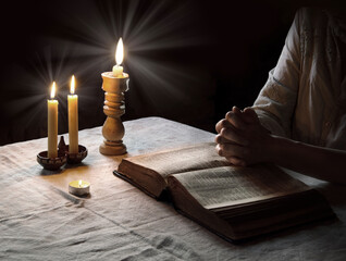 Woman reading the Bible by candlelight