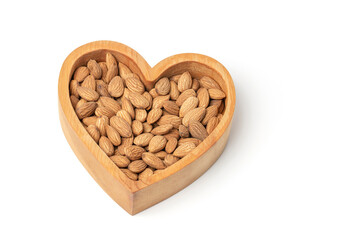 Almond in a heart shaped wooden plate isolated on white background. Products for heart health. Copy...
