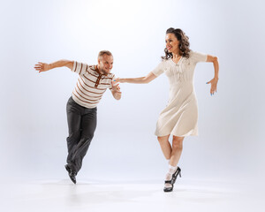 Astonished young dancing man and woman dance sport dances isolated on white background. 50s, 60s ,70s american fashion style.