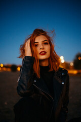 Portrait of a beautiful young woman with red air at the blue hour / sunset