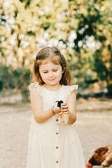 Little girl wear casual dress taking care of animals on true farm.