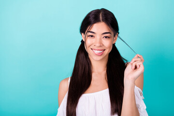 Portrait of gorgeous positive filipino person biting lip hold play hairdo tail isolated on teal color background