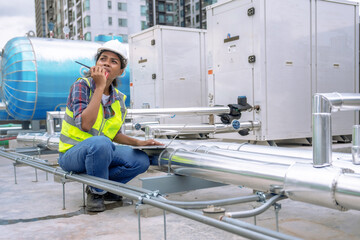 Female engineer inspects and controls the cooling system of a large factory air conditioner.