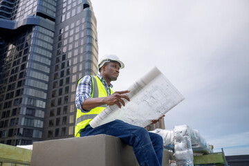 African male civil engineer inspects a commercial building construction site in a real estate...