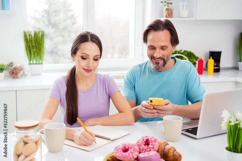 Wall mural photo of cute cheerful age boyfriend girlfriend wear t-shirts typing modern gadget writing breakfast