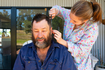 Girl carefully cutting her dad's hair