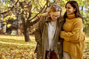 Fototapeta premium Senior woman with her adult daughter walking at the park during the autumn
