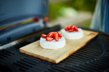 Fototapeta Woman hand put strawberry on grill camembert cheese outdoor obraz