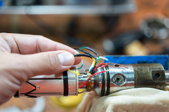 An electrician's hand is choosing the electricity wire of electronic equipment. Industrial working scene, close-up and selective focus.