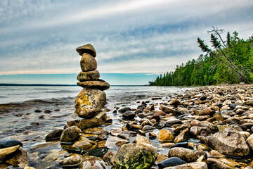 rock cairn on the rocky shore of a lake  - Powered by Adobe