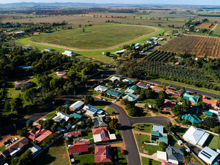 Aerial view of homes in housing area boarding edge of town, farm and race course oval