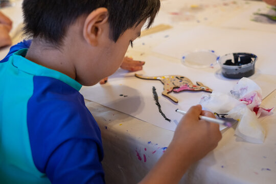 a kid painting a kangaroo in aboriginal styling