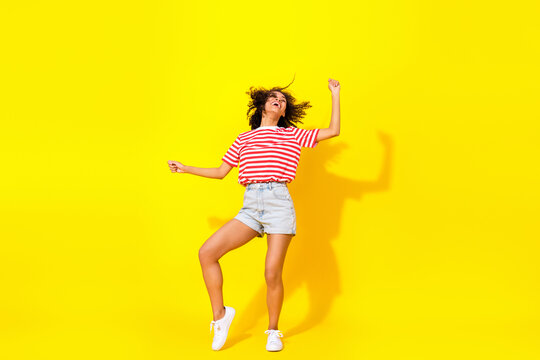 Full body photo of brunette hooray lady dance wear t-shirt shorts sneakeers isolated on yellow color background
