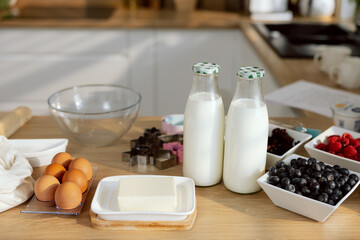 Close-up shot fresh healthy products milk eggs butter blueberry raspberry for preparing pie pancakes cheesecakes n the wooden rable . In the kitchen.