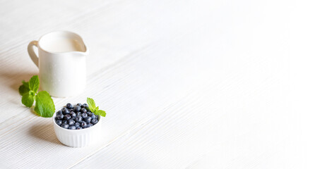 Fresh forest blueberries and milk on white wooden table. Healthy organic food. Banner. Copy space.