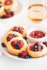 Homemade cottage cheese pancakes with fresh berries on white table