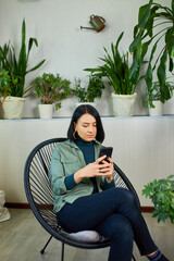 Fototapeta Woman chatting using smartphone, sitting on armchair at home obraz