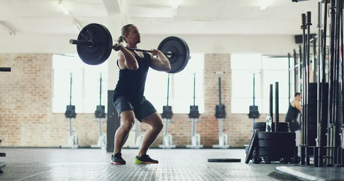 Fitness, wellness and an exercising athlete weightlifting at gym. Fit male pumping iron, serious about body and gain goals. Active guy training muscles, doing cardio, strength and endurance workout